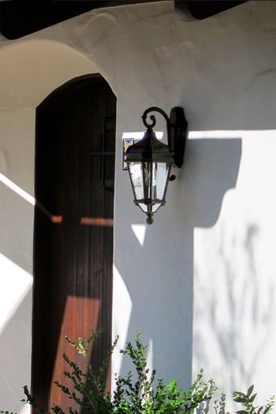 a Spanish Wood Entry Door is Nestled into a Deeply Recessed Plaster Alcove and a Lantern Style Light Provides a Sense of Warmth to This Entry at a Santa Barbara California Spanish Style Home