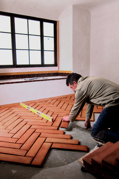 a Santa Barbara California Tile Setter Places an Oversized Clay Floor Tile to Create a Herringbone Pattern Floor in a Spanish Home in Montecito California