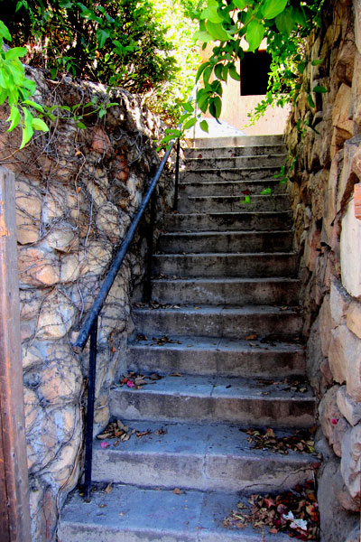 Old Santa Barbara Staircase with Sandstone Walls and a Black Iron Railing Leads Up to a Spanish Home on the Riviera.