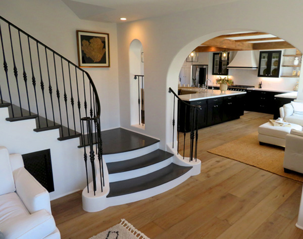 a Modern Spanish Remodel in Santa Barbara, California Showing a Grand Staircase and a Kitchen Beyond.