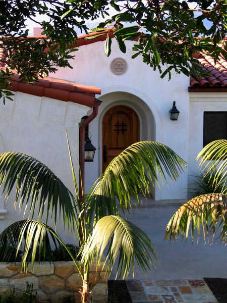 a Newly Completed Small Custom Spanish Revival Home Design by Jeff Doubét Features a Modest Tower Entry, Round Top Wood Door and a Cast Concrete Medallion Detail.