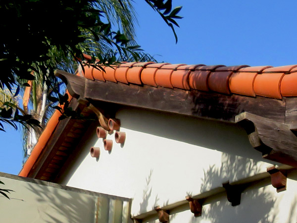 A photo of a gable end of a Spanish-style home in Santa Barbara, California that includes decorative and functional terracotta clay vents embedded in the stucco.
