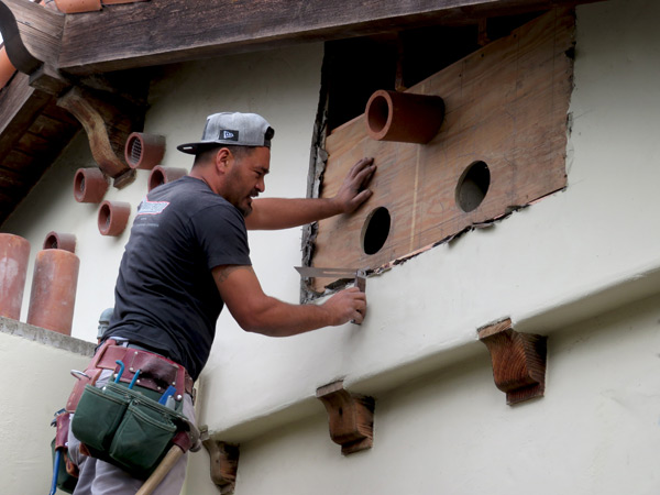 Clay vent installation process.  A young carpenter uses a special tool to figure out the consistent angle he will use to install clay vents in a Spanish-style home in Santa Barbara, CA.