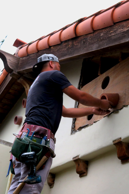 A Santa Barbara carpenter works on the first steps of installing clay vents to ventilate a small attic space of a Spanish-style home in Santa Barbara, CA.