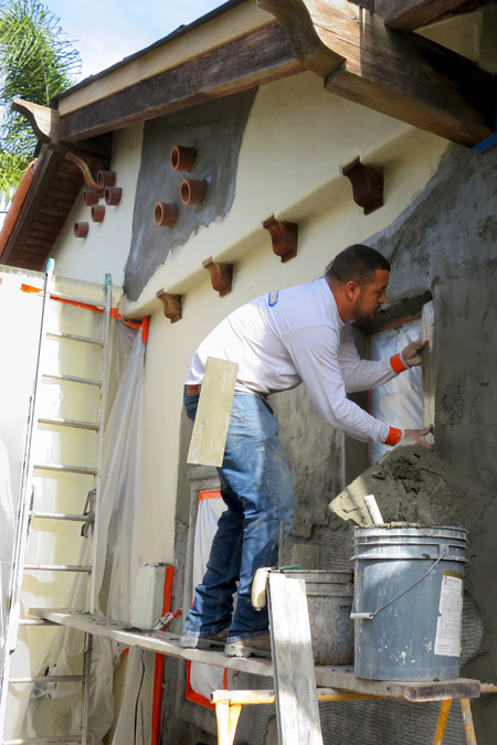 A professional plasterer works on adding a layer of stucco around a Spanish window in a Spanish-style home being remodeled in Santa Barbara, CA.