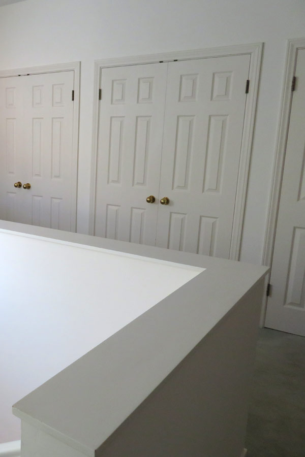 An ugly second story landing of a santa barbara fixer upper home has "vanilla white" walls, doors and bad carpet. A "before" photo for a major renovation.